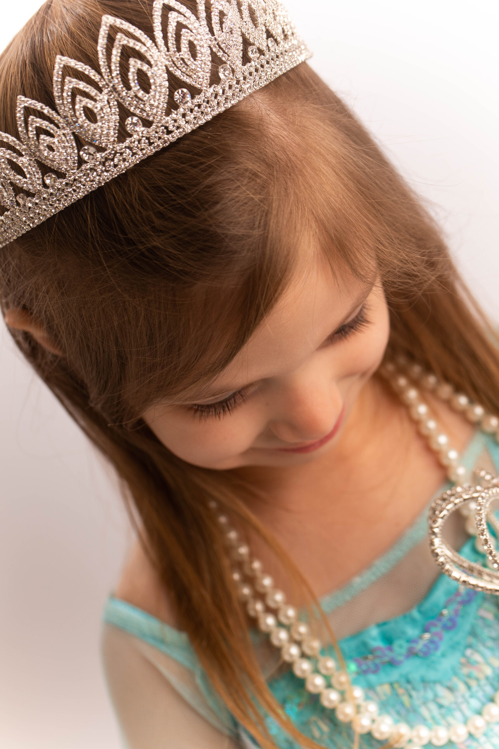 Young girl wearing tiara and pearl necklaces