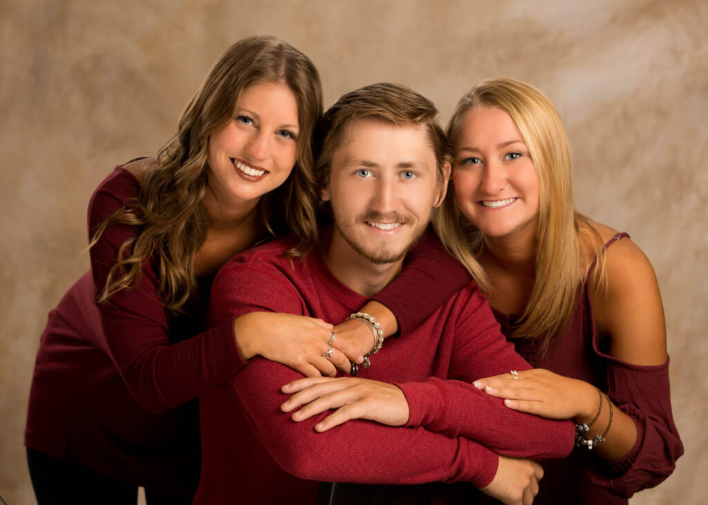 Three smiling adults posing in studio portrait